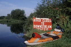 Red caution sign and kayak on River Thames