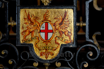 Finely painted City of London dragons on golden plate mounted on black wrought iron gate at St Margaret Pattens Church