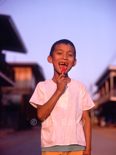 Smiling boy licking candy on a stick in Northeast Thailand