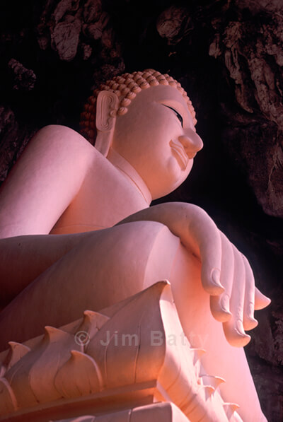 Huge pink buddha statue looming overhead in mouth of Erawan Cave, Northeast Thailand