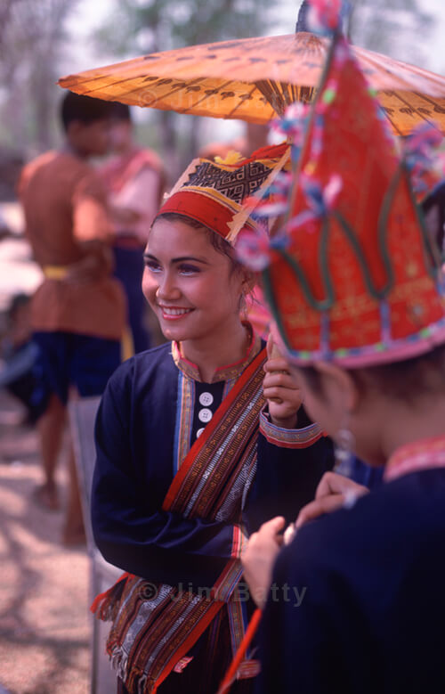 Focus is on a pretty Khmer woman dancer holding a paper umbrella in Northeast Thailand
